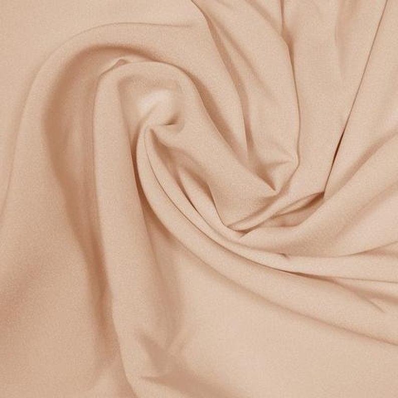 May include: A close-up of a smooth, light beige fabric with soft folds and wrinkles.