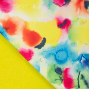 May include: A textile fabric featuring a vibrant watercolor pattern with blended splashes of bright yellow, hot pink, sky blue, and lime green. The design displays soft, organic edges where colors bleed into one another on a white base.