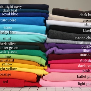 May include: A stack of folded fabric swatches in various colors, including midnight navy, dark teal, royal blue, turquoise, aqua, baby blue, mint, dark olive, hunter green, kelly green, lime, mustard, yellow, light yellow, orange, red, dark brown, cream, white, black, 2-tone charcoal, heather gray, purple, lilac, maroon, fuchsia, dark coral, pink, ballet pink, and light pink.