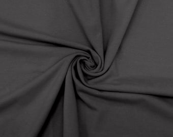 May include: A close-up of a dark gray fabric with a soft, smooth texture. The fabric is folded and draped, creating a swirling pattern.