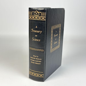 Puede incluir: Un libro de tapa dura negro titulado A Treasury of Science con letras doradas y patrones de líneas doradas decorativas en el lomo y la portada. El lomo enumera a los editores Harlow Shapley, Samuel Rapport y Helen Wright en texto dorado.