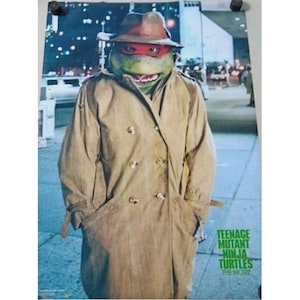May include: A poster featuring a Teenage Mutant Ninja Turtle character wearing a brown fedora hat and a tan double-breasted trench coat. The character has green skin and a red eye mask. The text Teenage Mutant Ninja Turtles The Movie is visible.