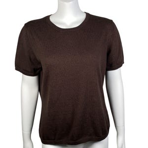 May include: A brown short-sleeved sweater with a crew neck. The knitted top is a solid colour and appears to be made of a soft material. The sweater is displayed on a white mannequin.