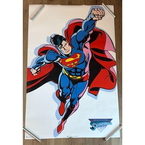 Può includere: Un poster rettangolare con un'illustrazione a fumetti di Superman che vola in avanti con un pugno teso. Il personaggio indossa una tuta blu con mantello rosso, stivali rossi e una cintura gialla. È stampato il testo "BETTER THAN EVER SUPERMAN".