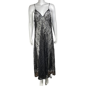 May include: Black lace slip dress with spaghetti straps and a V-neckline. The dress is floor-length and features a delicate floral lace pattern. The dress is displayed on a mannequin.