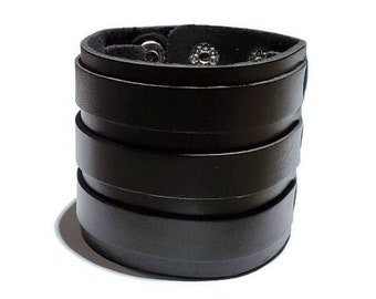 May include: A black leather bracelet with multiple layers and silver metal accents.