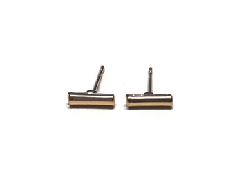 May include: A pair of gold bar stud earrings with silver posts.