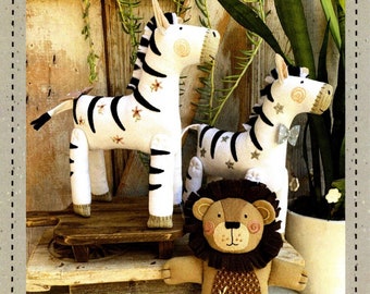 May include: A sewing pattern for a 13-inch tall stuffed lion and zebra. The pattern includes two variations for the zebra. The image shows the finished stuffed animals, a lion with a brown mane and a zebra with black and white stripes.