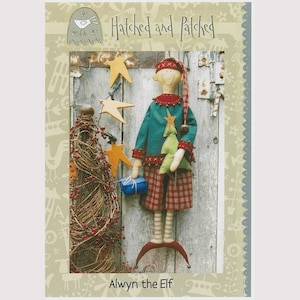 May include: A handmade elf doll with a teal jacket, red plaid shorts, and a matching hat. The doll holds a green Christmas tree and a blue gift. The background includes wooden stars and the text "Hatched and Patched" and "Alwyn the Elf".