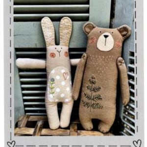 May include: Two handmade stuffed toys: a bear and a bunny. The bear is brown with a cream-colored face and embroidered details. The bunny is beige with long ears and a polka-dot belly. The toys are approximately 14 inches tall. The text "Heart to Hand" is at the bottom.