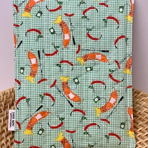 May include: A green and white checked oven mitt featuring a repeating pattern of cartoon sausages, red chilli peppers, and grilling tools. The mitt has a hanging loop and a small tag that says "You are awesome."