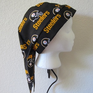 Peut inclure: Bandeau de tête en tissu noir et or sur le thème des Steelers de Pittsburgh avec une longue queue. Le tissu présente un motif répété du logo des Steelers et du mot "Steelers".
