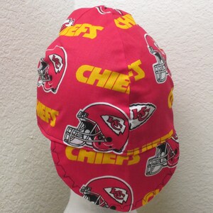 May include: Red and yellow welding cap with a pattern of Kansas City Chiefs logos, including the team's helmet and the word "Chiefs".
