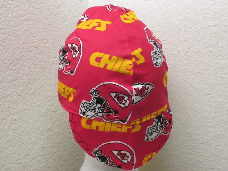 May include: Red and yellow welding cap with a pattern of Kansas City Chiefs logos, including the team's helmet and the word "Chiefs".