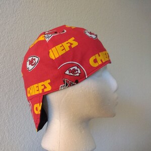 May include: Red and yellow fabric welding cap with the Kansas City Chiefs logo and the word "Chiefs" repeated on the fabric.