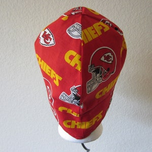 May include: Red and yellow fabric hat with the word "Chiefs" repeated and a football helmet logo.