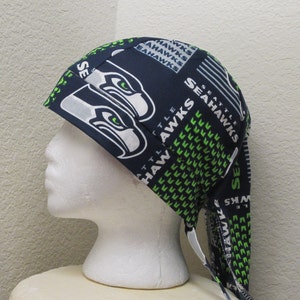 May include: A blue and green patterned bandana with the Seattle Seahawks logo and the words "Seattle Seahawks" repeated throughout. The bandana is tied on a white mannequin head.