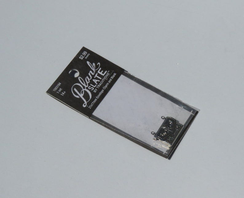 May include: A pack of 14 silver 21x17mm envelope charms and blanks from Blank Slate by Traditions. The pack is labelled with the price &pound;2.99.