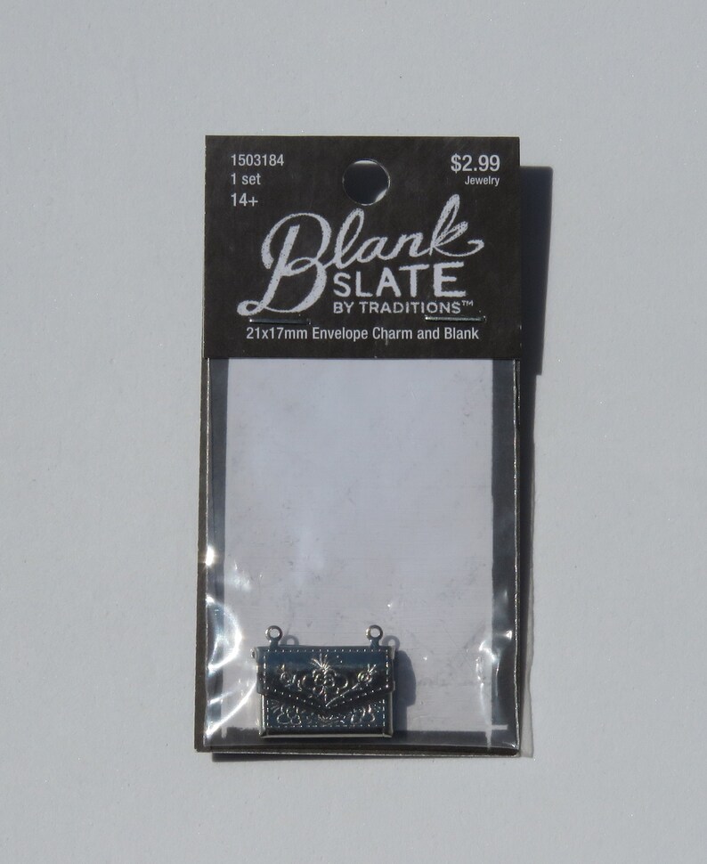 May include: A silver metal envelope charm with a floral design. The charm is 21mm x 17mm and is packaged on a card that reads "Blank Slate by Traditions 21x17mm Envelope Charm and Blank".