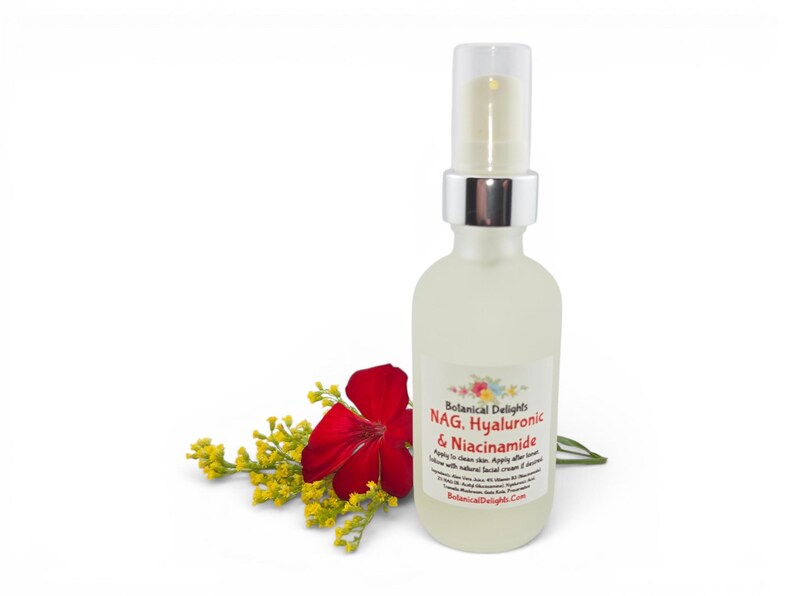 May include: A clear glass bottle with a silver pump top, labeled "NAG. Hyaluronic & Niacinamide" from Botanical Delights. A red flower and yellow sprigs are placed to the left of the bottle against a white background.