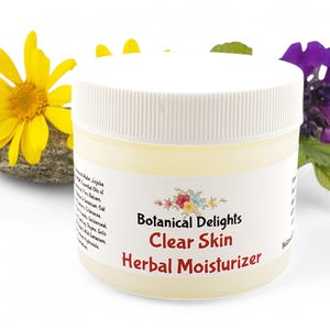a jar of clear skin herb moistizer next to a flower