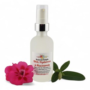 May include: A frosted glass bottle with a silver pump top, labeled "Botanical Delights NAG, Hyaluronic & Niacinamide." A pink flower and green leaves are next to the bottle. The bottle contains a clear liquid.