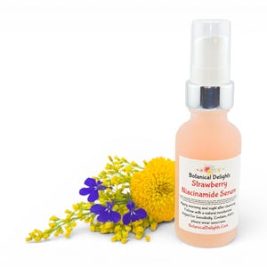 May include: A peach-colored serum bottle with a silver pump and a white label that reads "Botanical Delights Strawberry Niacinamide Serum." The bottle is next to a cluster of yellow and purple flowers. The background is white.