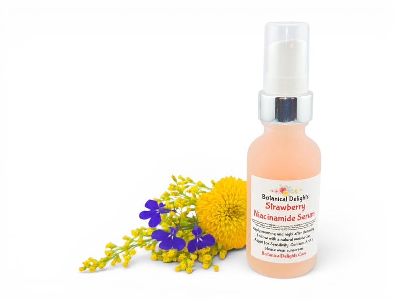 May include: A peach-colored serum bottle with a silver pump and a white label that reads "Botanical Delights Strawberry Niacinamide Serum." The bottle is next to a cluster of yellow and purple flowers. The background is white.