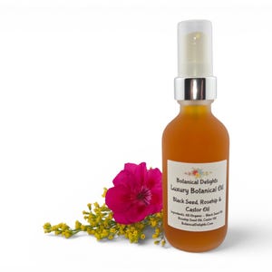 May include: A clear glass bottle with a silver pump top, filled with amber-colored liquid. The label reads "Botanical Delights Luxury Botanical Oil Black Seed, Rosehip & Castor Oil." A pink flower and yellow sprigs are next to the bottle.