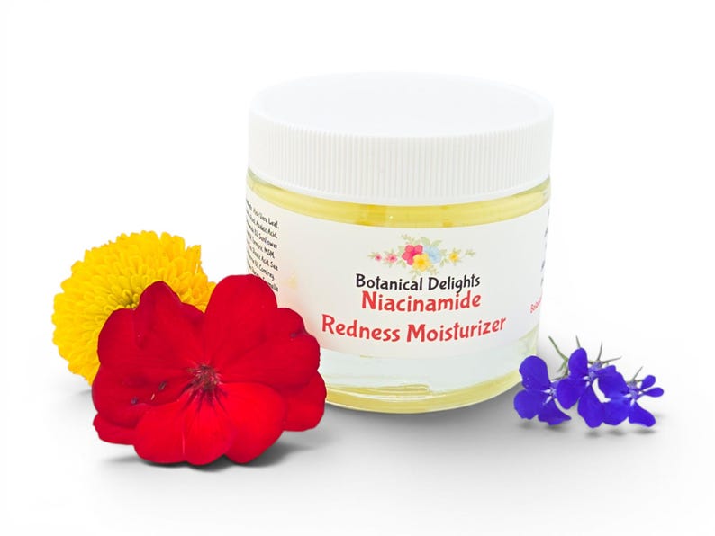 May include: A jar of Botanical Delights Niacinamide Redness Moisturizer with a white lid and a label with floral accents. The jar is surrounded by a red flower, a yellow flower, and a cluster of small blue flowers.
