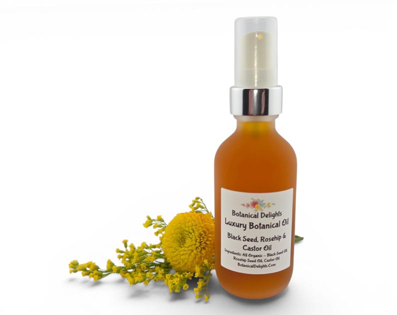 May include: A frosted amber glass bottle with a silver pump top, containing a golden liquid. The label reads "Botanical Delights Luxury Botanical Oil Black Seed, Rosehip & Castor Oil." Yellow flowers and foliage are arranged beside the bottle.