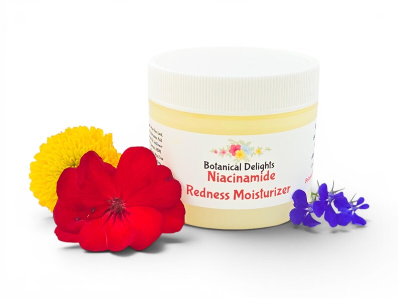 May include: A jar of Botanical Delights Niacinamide Redness Moisturizer with a white lid and a cream-colored body. The jar is surrounded by a yellow flower, a red flower, and a sprig of blue flowers. The product label is visible.
