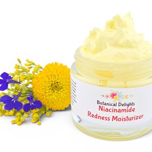 May include: A jar of yellow cream moisturizer with the text "Botanical Delights Niacinamide Redness Moisturizer." The jar is next to a yellow flower and blue and yellow sprigs.