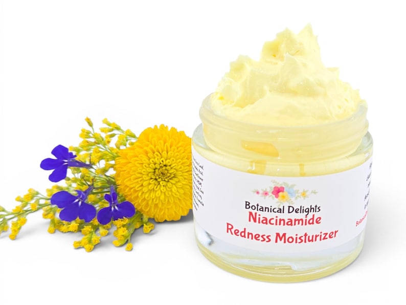 May include: A jar of yellow cream moisturizer with the text "Botanical Delights Niacinamide Redness Moisturizer." The jar is next to a yellow flower and blue and yellow sprigs.