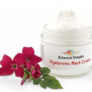 Op de afbeelding: Een witte pot Hyaluronzuur Halscr&egrave;me van Botanical Delights. De pot is open en de cr&egrave;me is zichtbaar. Een bos roze bloemen staat op de voorgrond.