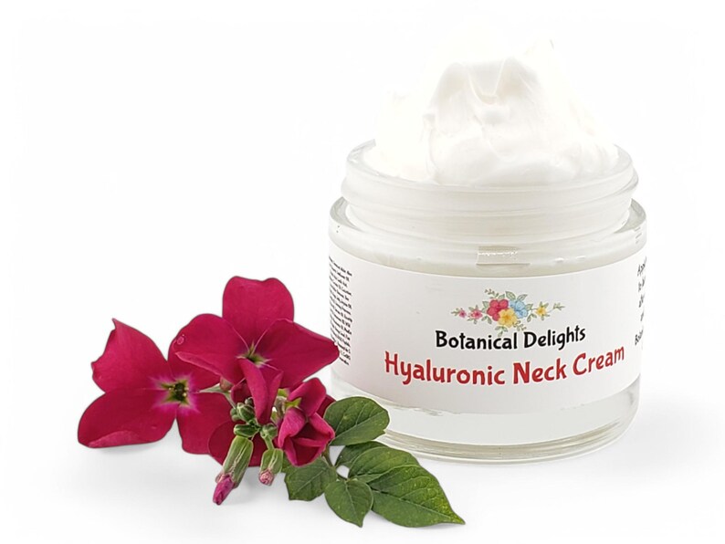Op de afbeelding: Een witte pot Hyaluronzuur Halscr&egrave;me van Botanical Delights. De pot is open en de cr&egrave;me is zichtbaar. Een bos roze bloemen staat op de voorgrond.