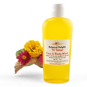 May include: A yellow bottle of Botanical Delights TV Tamer Face & Body Wash. The bottle has a white cap and a label with the product name and instructions for use. The bottle is sitting on a white background with yellow and red flowers.