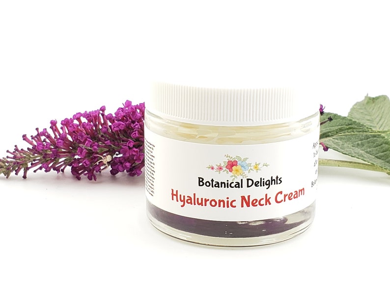 Op de afbeelding: Een witte pot met een wit deksel, gevuld met een gele cr&egrave;me. De pot heeft een etiket met de tekst "Botanical Delights Hyaluronic Neck Cream".