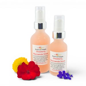 May include: Two bottles of Botanical Delights Strawberry Niacinamide Serum with white pump tops. The bottles are filled with a pink liquid and have labels. A yellow flower, a red flower, and a cluster of blue flowers are in front of the bottles.