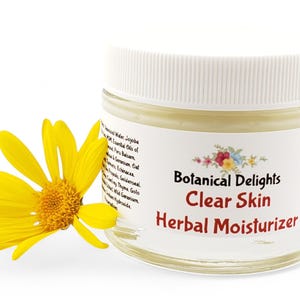 a jar of clear skin herb moistizer next to a yellow flower