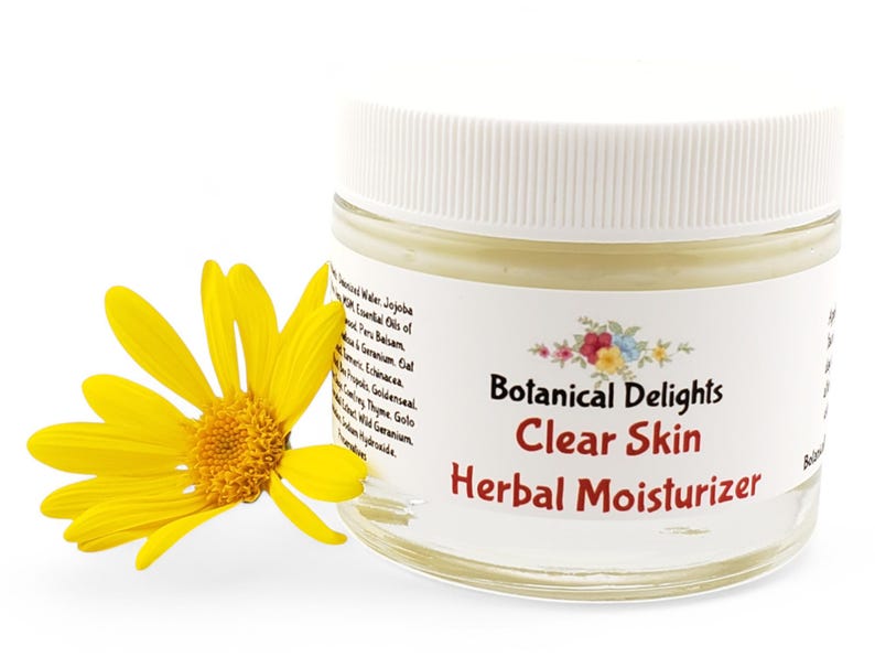 a jar of clear skin herb moistizer next to a yellow flower
