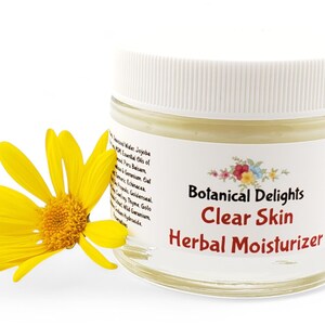 a jar of clear skin herb moistizer next to a yellow flower
