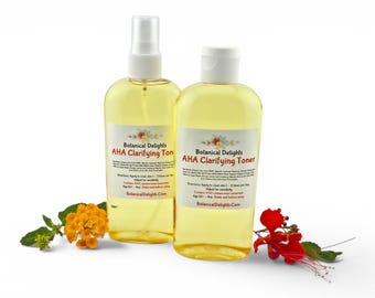 Może przedstawiać: Dwie przezroczyste plastikowe butelki toniku Botanical Delights AHA Clarifying Toner z żółtym płynem. Każda butelka ma białą etykietę z czerwonym i czarnym tekstem, zawierającą składniki i instrukcje. Jedna butelka ma rozpylacz, druga zamykaną nasadkę.