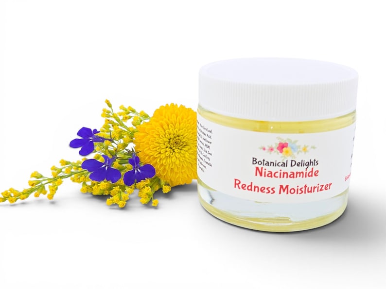 May include: A jar of Botanical Delights Niacinamide Redness Moisturizer with a white lid. The jar is next to a bouquet of yellow and blue flowers. The label on the jar has the product name and brand.
