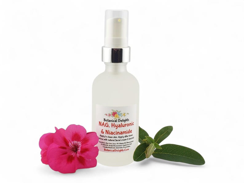 May include: A clear glass bottle with a silver pump top, labeled "Botanical Delights NAG, Hyaluronic & Niacinamide." A pink flower and green leaves are next to the bottle. The bottle contains a skincare product.