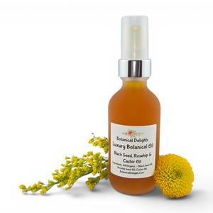 May include: A frosted glass bottle of Botanical Delights Luxury Botanical Oil with a silver pump. The label reads "Black Seed, Rosehip & Castor Oil." Yellow flowers and a yellow pom-pom shaped flower are next to the bottle. The background is white.