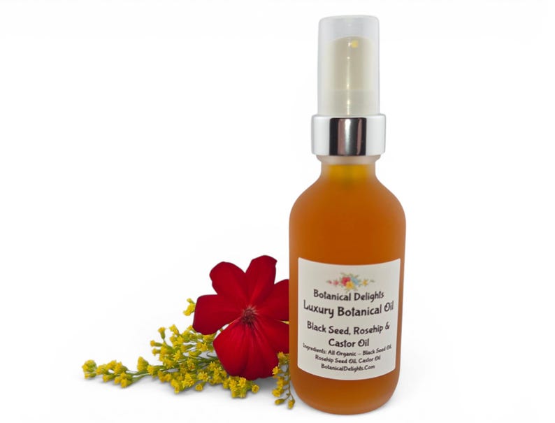 May include: A frosted glass bottle of Botanical Delights Luxury Botanical Oil. The bottle has a silver pump and contains a golden-orange liquid. A red flower and yellow sprigs are next to the bottle. The label reads "Black Seed, Rosehip & Castor Oil."