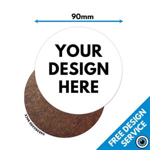 以下が含まれることがあります： 太字の黒い文字で「YOUR DESIGN HERE」と書かれた白い円形のステッカー。ステッカーの直径は90mmで、裏面は茶色のハードボードです。青いコーナーグラフィックには「FREE DESIGN SERVICE」と書かれています。