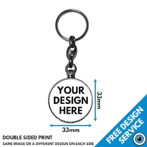 Könnte beinhalten: Ein silberner Schlüsselanhänger mit einem runden, 33 mm großen Metallanhänger. Der Anhänger hat einen weißen Hintergrund und schwarzen Text, der "YOUR DESIGN HERE" lautet. Der Schlüsselanhänger ist doppelseitig, sodass auf jeder Seite ein anderes Design möglich ist.