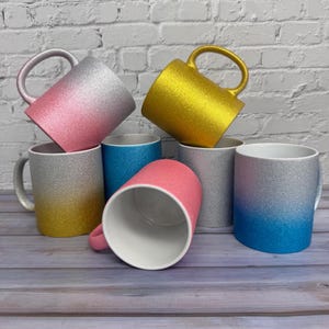 Puede incluir: Una colecci&oacute;n de siete tazas de cer&aacute;mica con un acabado brillante en varios colores, incluyendo oro, plata, rosa y azul. Algunas tazas presentan un efecto de color degradado, mientras que otras son de colores s&oacute;lidos. Cada taza tiene un interior blanco.